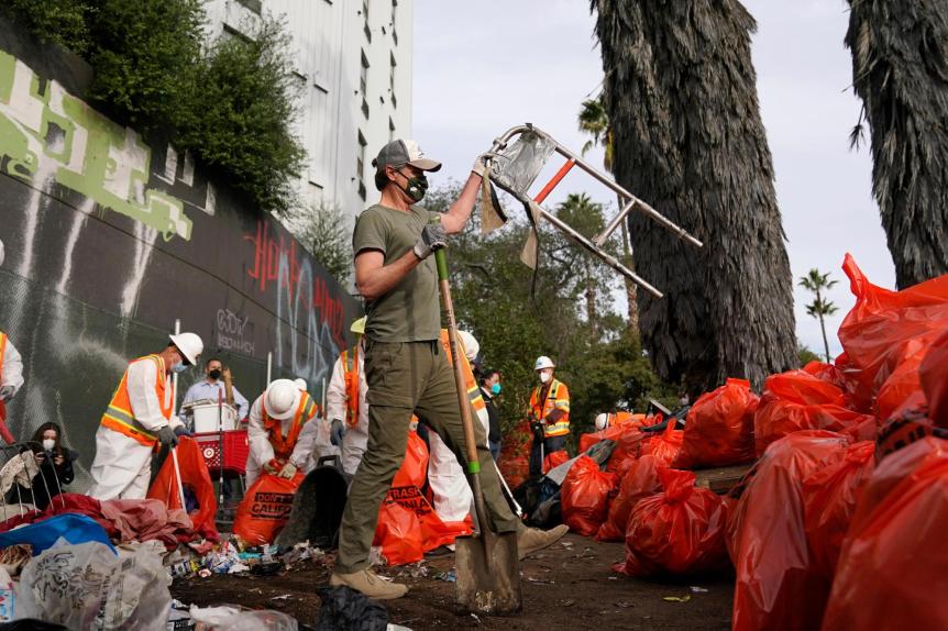 California Gov. Gavin Newsom, center, helps clean a homeless encampment alongside a freeway on Jan. 12, 2022, in San Diego. Newsom proposed a plan on Thursday, March 3, 2022, to force homeless people with severe mental health and addiction disorders into treatment. (AP Photo/Gregory Bull, File)